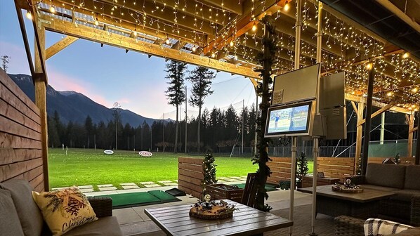 Un espace de détente intérieur, confortable et accueillant, avec vue sur un champ verdoyant et des montagnes.