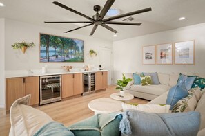 A modern living room with a ceiling fan, a kitchen with wooden cabinets, and a dining area. - Palm 2 - River Views, Private Dock & Boat Launch (Parker)