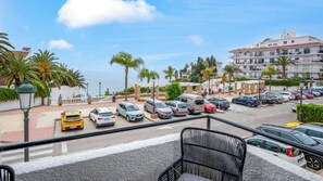 Ein Hotel an der Küste mit Parkplatz, Meerblick und Balkon mit Stuhl.