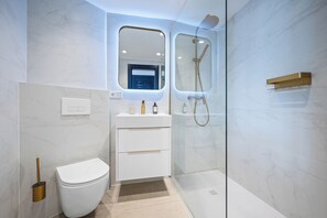 Een moderne badkamer met toilet, wastafel en douchecabine.
