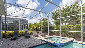 Ein überdachter Pool mit Liegestühlen und einer Glaskonstruktion.