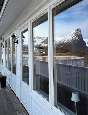 A covered porch with large windows overlooking a snowy mountain. - Senja Living Sea View apartment (Troms)