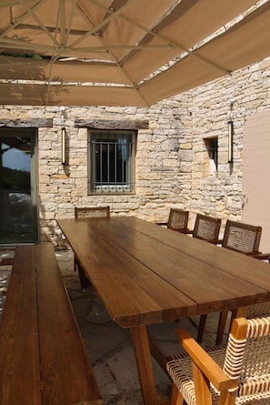 A stone-walled outdoor dining area with a wooden table and chairs.