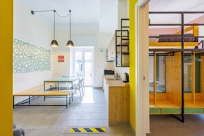 Ein modernes Interieur mit Essbereich, Küche und Schlafgalerie, die über eine Holzleiter erreichbar ist.