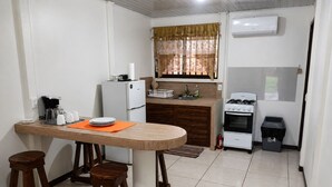 Une cuisine de taille réduite avec un îlot central, un réfrigérateur, une cuisinière et un évier.
