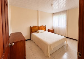 A bedroom with a wooden bed, a nightstand, and a wooden dresser.