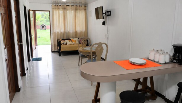 Une cuisine équipée d’une table à manger, de chaises, d’une machine à café et d’un téléviseur fixé au mur.