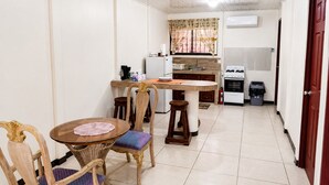 Une cuisine compacte comprenant un coin repas, un réfrigérateur, une cuisinière et une poubelle.