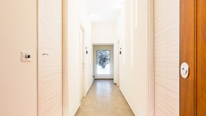 A hotel hallway with a welcome mat, light-colored walls, and wooden flooring. - Solaris Studio - Solaris Suites (Naples)