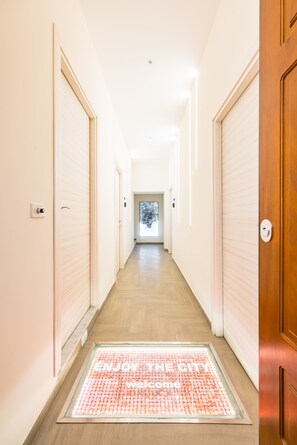 Un pasillo de hotel con felpudo, paredes de colores claros y suelo de madera.