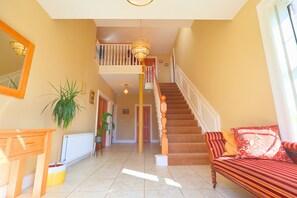 Ein geräumiger Wohnbereich mit Treppe, einer Couch, einem Tisch und einer Zimmerpflanze.