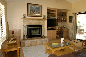 Ein Wohnzimmer mit Kamin, Fernseher und Essbereich mit Tisch und Stühlen.