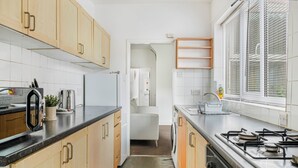 Een moderne keuken met houten kastjes, een fornuis, een koelkast en een wasmachine.