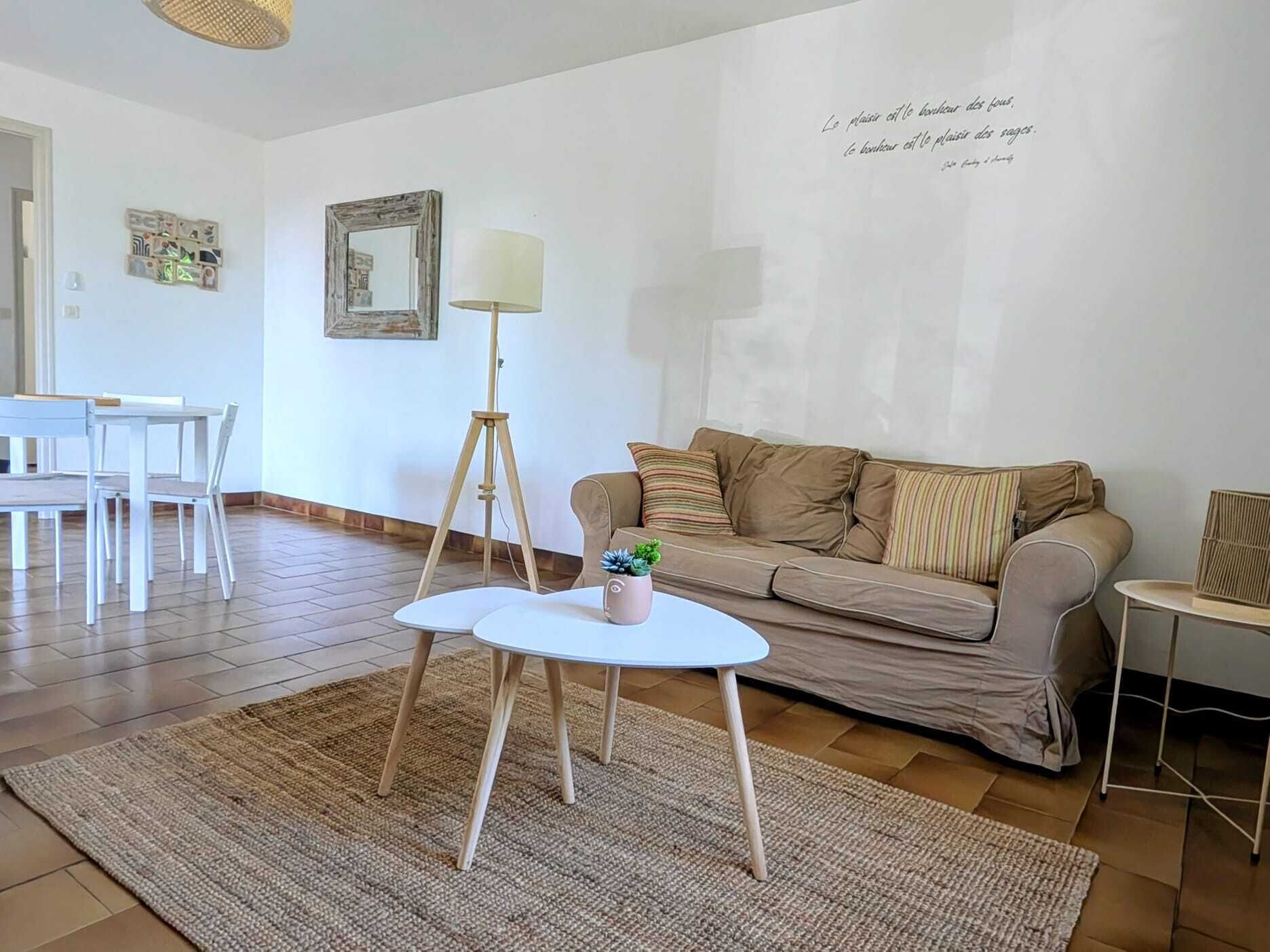 Un salón con sofá, una mesita redonda, una lámpara de pie y un trípode.