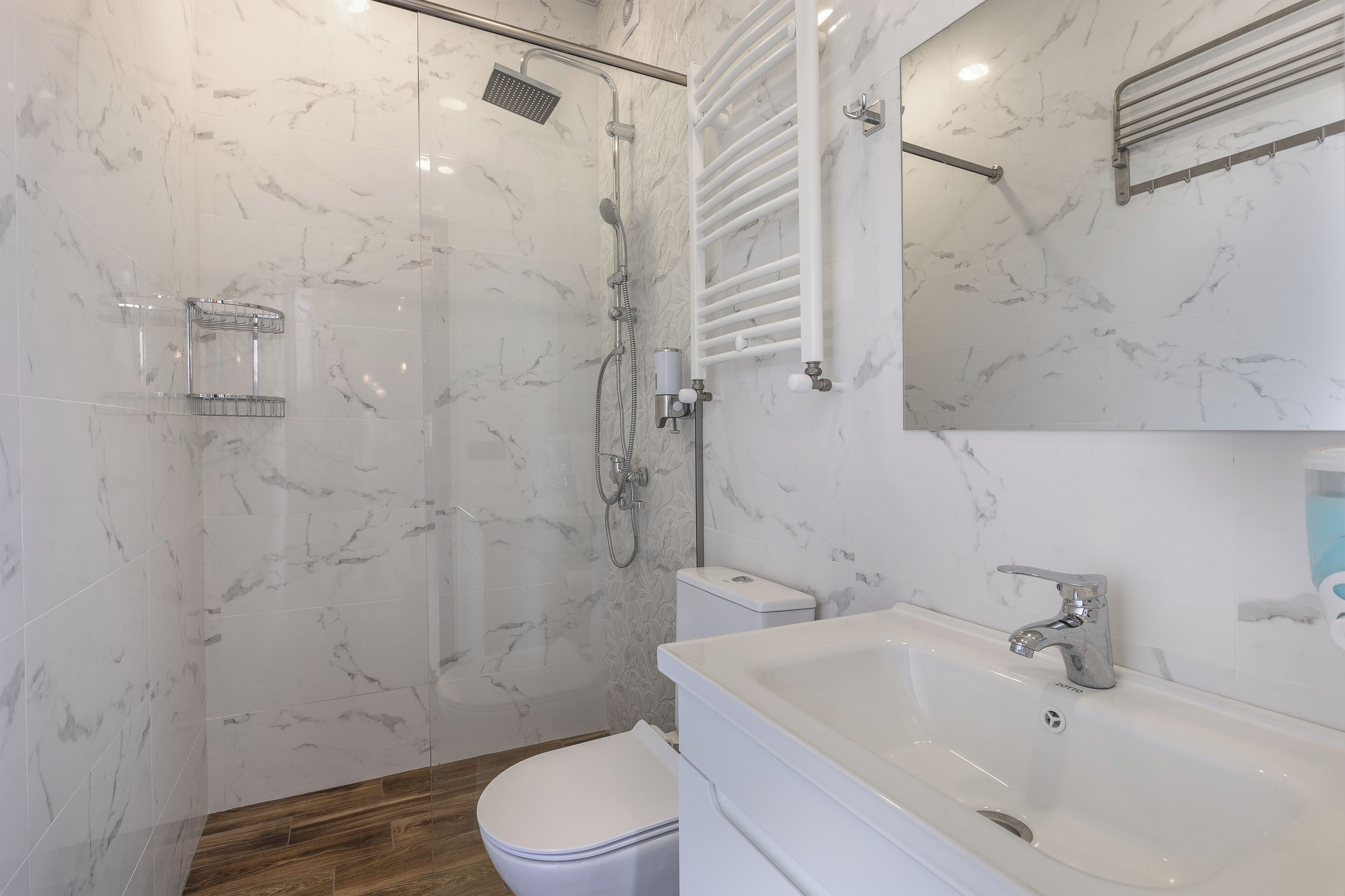 A bathroom with a shower, toilet, sink, and mirror.