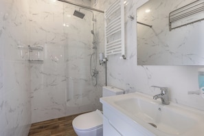 Un baño con ducha, inodoro, lavabo y espejo.