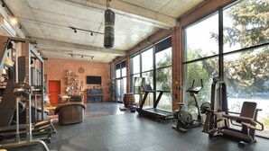 A gym with exercise equipment, a treadmill, and large windows.