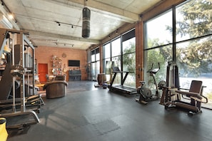 A gym with exercise equipment, a treadmill, and large windows.