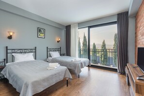 Habitación de hotel con dos camas, televisión y balcón con vistas.
