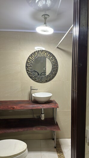 A bathroom with a round mirror, white sink, and a wooden vanity. - Delightful 1-bedroom fully equipped cabin in Nuevo Colón welcomes your stay! (Nuevo Colón)