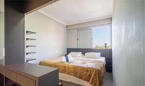Ein Schlafzimmer mit Bett, Schreibtisch, Fenster und Blick ins Freie.