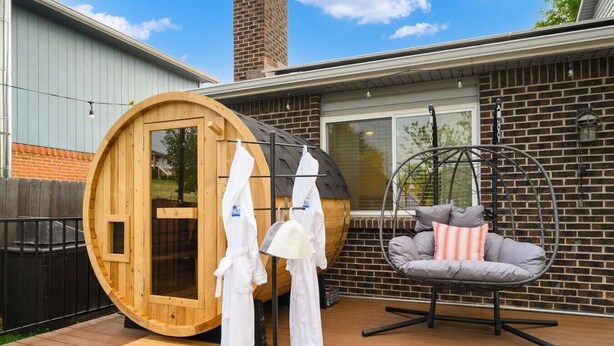 Ein Holzbottensauna, ein Hängesessel mit Kissen und eine Holzterrasse.