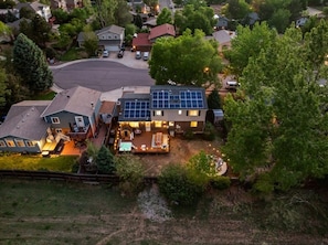 A residential property with a large backyard, solar panels, and a well-lit outdoor area. - Rangewell Retreat Hot Tub, Sauna, Fire Pit, Games, Groups & Families (Arvada)