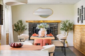 A dining area with a fireplace, a table set with plates and glasses, and chairs around the table. - Rangewell Retreat: Hot Tub, Sauna, Fire Pit, Games for Groups & Families (Arvada)