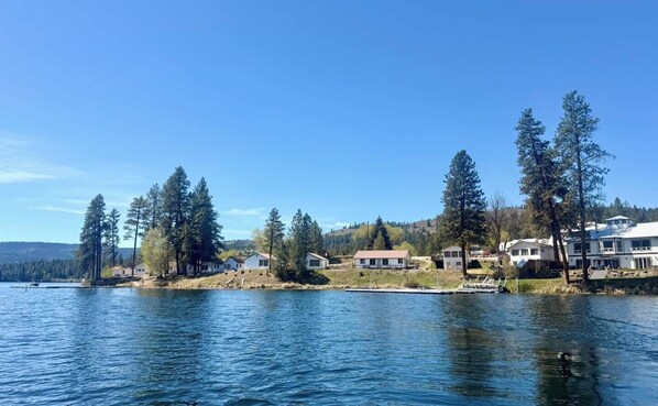 A lakeside property with houses, trees, and a dock.