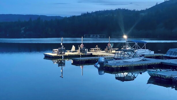 A calm lake at dusk with docked boats and a pier.