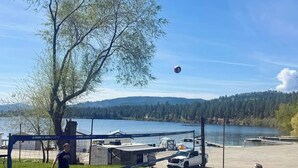 A volleyball game in a park with a lake and mountains in the background.
