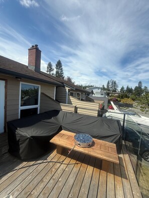 A deck with a covered seating area, a table, and a view of a residential neighborhood. - Passage view 2,0
Close to beaches and shopping, pet friendly and family friendly (Campbell River)