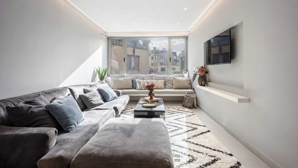 Una sala moderna con un sofá, una mesa de centro y un televisor montado en la pared.