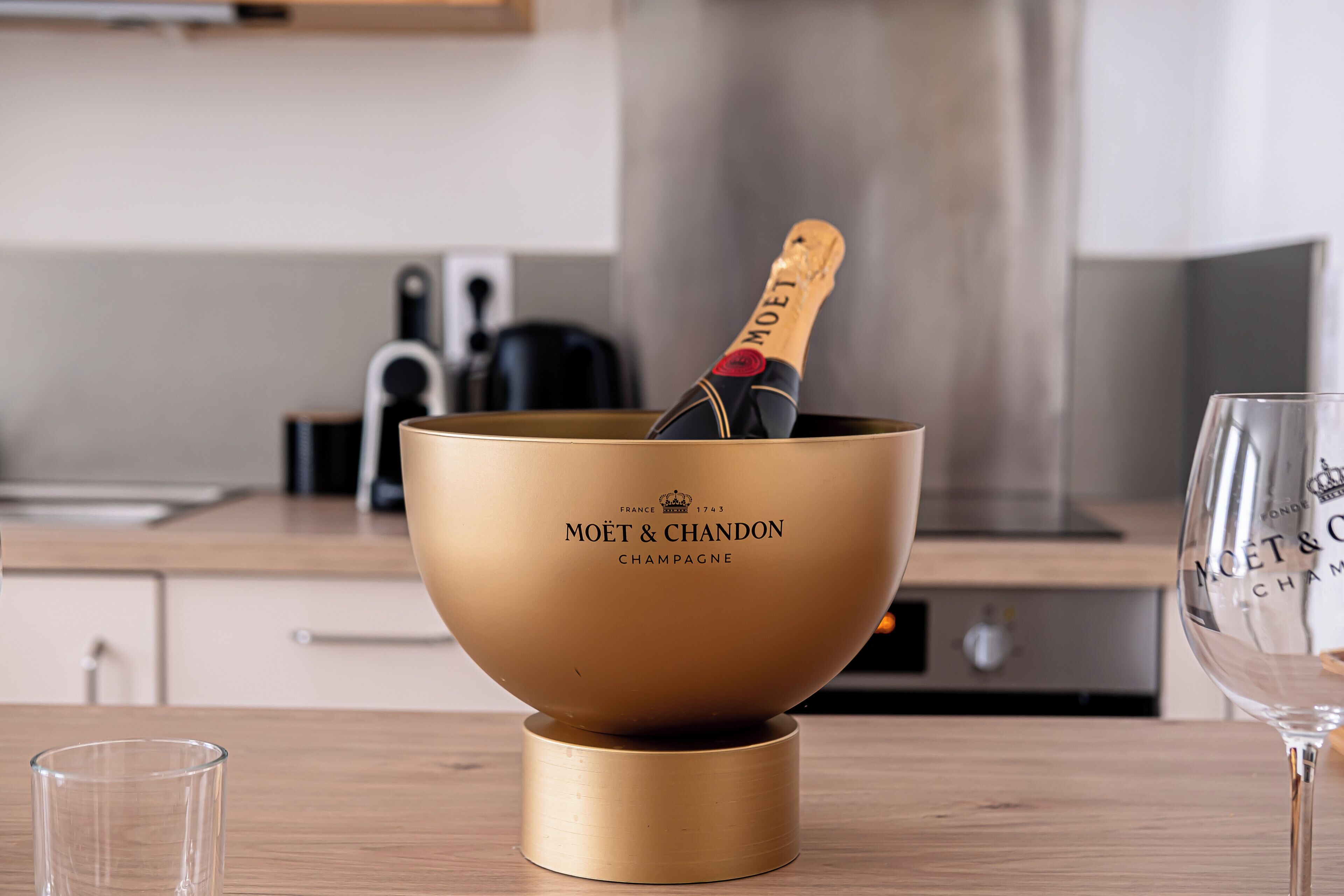 A gold Moët & Chandon champagne bottle in a gold bowl on a wooden table.