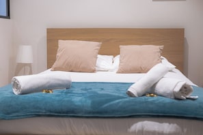 A neatly made bed with a wooden headboard, two beige pillows, and a blue blanket. - Vrbo Property (Reims)