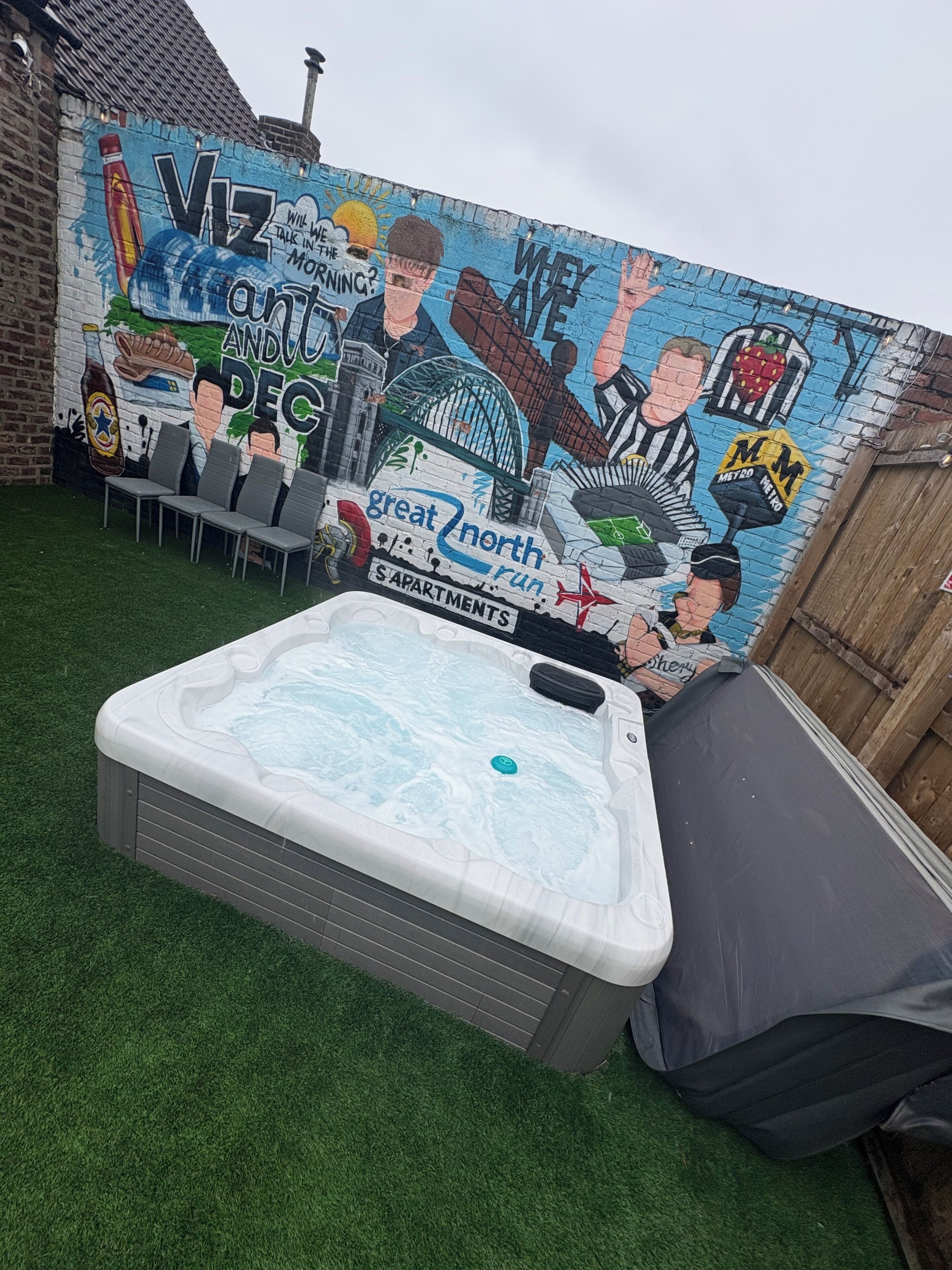 A hot tub in a backyard with a mural on the wall.