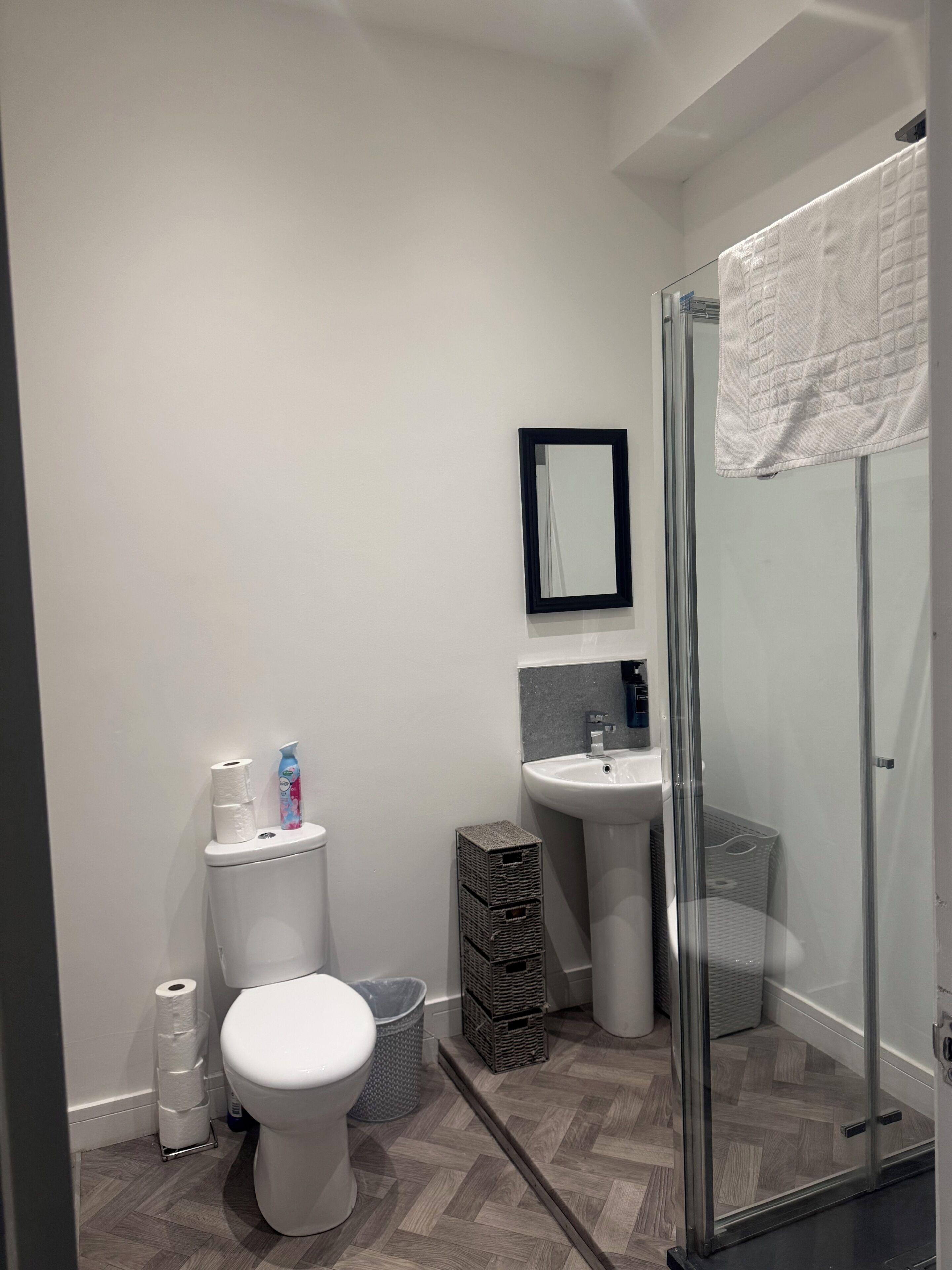 Un baño moderno con inodoro, lavamanos y cabina de ducha de vidrio.