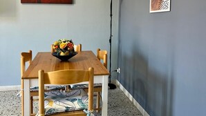 A dining area with a wooden table and chairs, a vase of flowers, and abstract art on the wall. - A Due Passi Dalla Certosa via Guglielmo Marconi 12, Certosa di Pavi (Certosa di Pavia)
