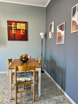 Un'area pranzo con un tavolo e sedie in legno, un vaso di fiori e un'opera d'arte astratta appesa al muro.