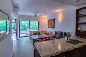 Een moderne woonkamer met een bank, eettafel en keuken, voorzien van granieten aanrechtbladen.