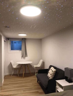 A room with a round table, two chairs, a sofa, a small bedside table, and a window with blinds. - Full privacy whole Unit 4+ bedrooms next to downtown & airport (CALGARY)