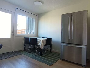 Una cocina compacta con mesa, sillas, un refrigerador y una ventana.