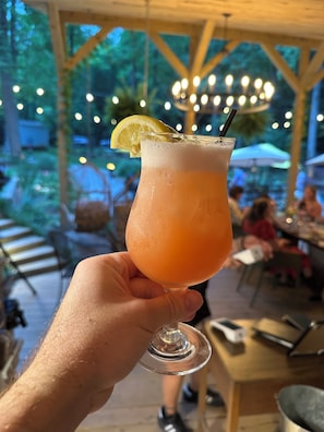 A hand holding a glass with a drink, a lemon slice, and a straw.