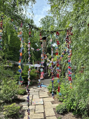 A garden pathway with a decorative archway adorned with colorful fabric.