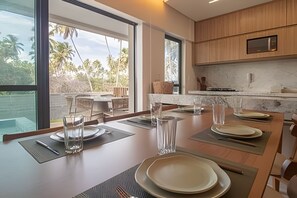 Een moderne keuken met een eethoek, grote ramen en uitzicht op palmbomen.