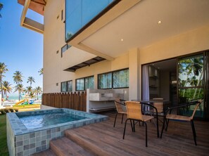 A modern outdoor pool area with a hot tub, wooden deck, and wicker chairs.