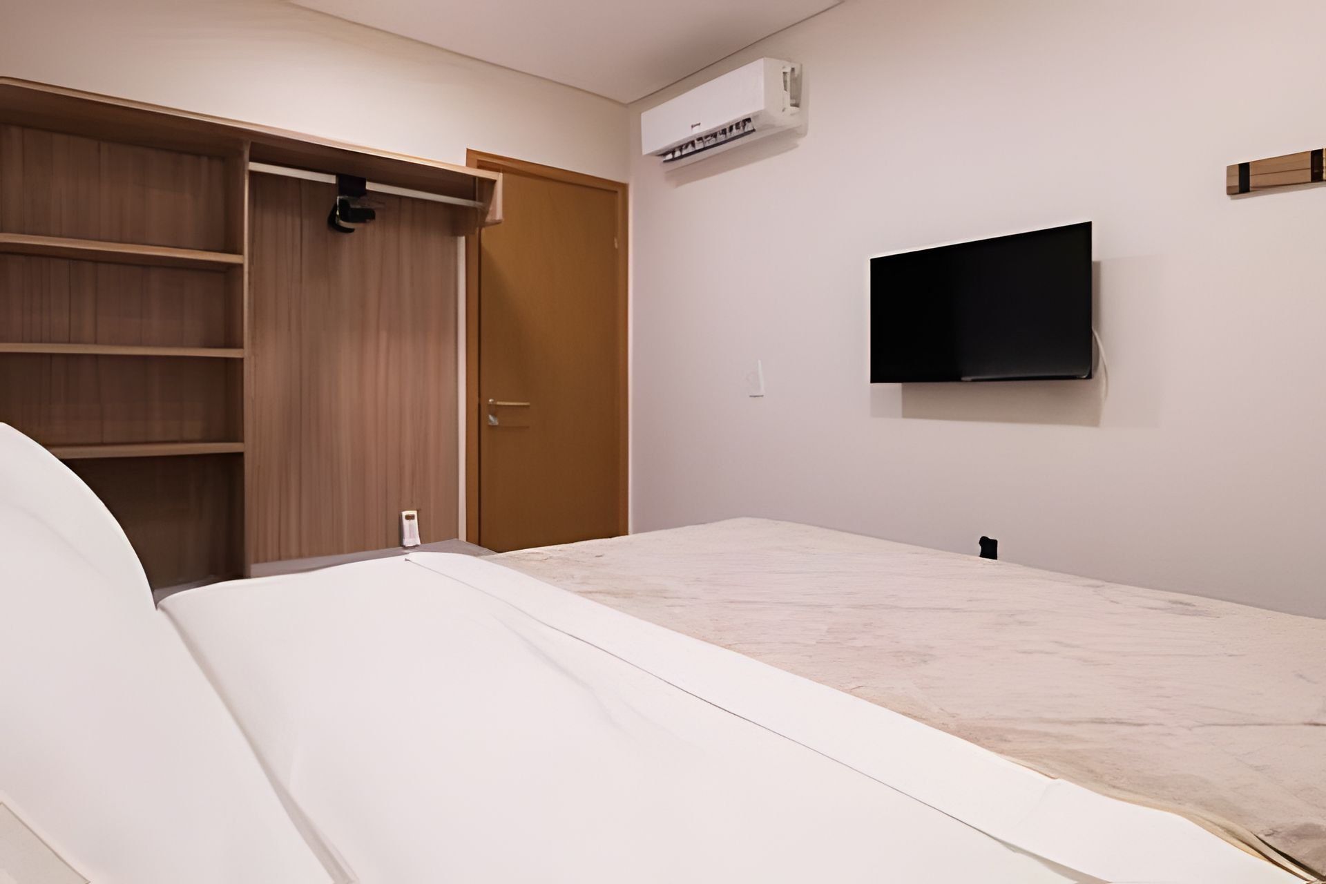 Een slaapkamer met een bed, een kledingkast, een televisie en een airconditioner.