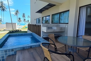 Un patio moderno al aire libre con piscina, una mesa de vidrio y sillas.