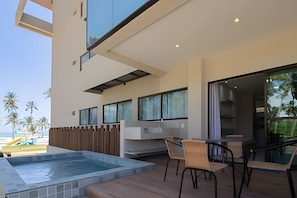 Un patio moderno al aire libre con un jacuzzi, una zona de estar y grandes ventanales con vistas a una piscina.