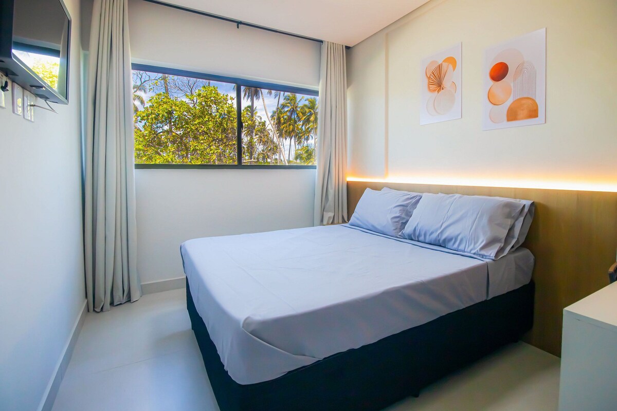 A modern bedroom with a large bed, a window with curtains, and wall art.